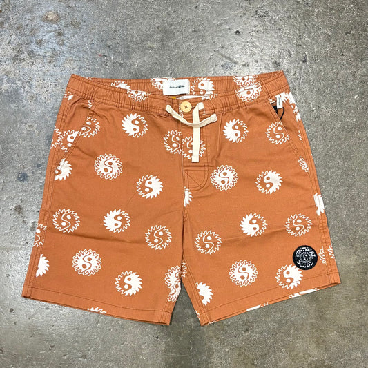 Orange shorts with white patterns on a gray concrete surface