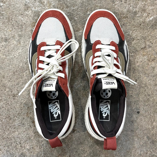 Pair of Vans sneakers with red, white, and black design on a concrete surface