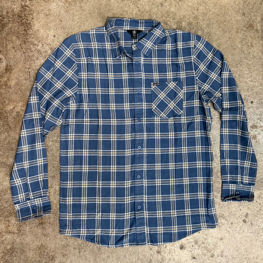 A Volcom Loreto flannel woven shirt with long sleeves, featuring a blue and white checkered pattern, a single chest pocket, and logo buttons.
