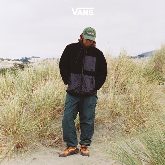 Man on a beach wearing Vans Crosspath in orange.