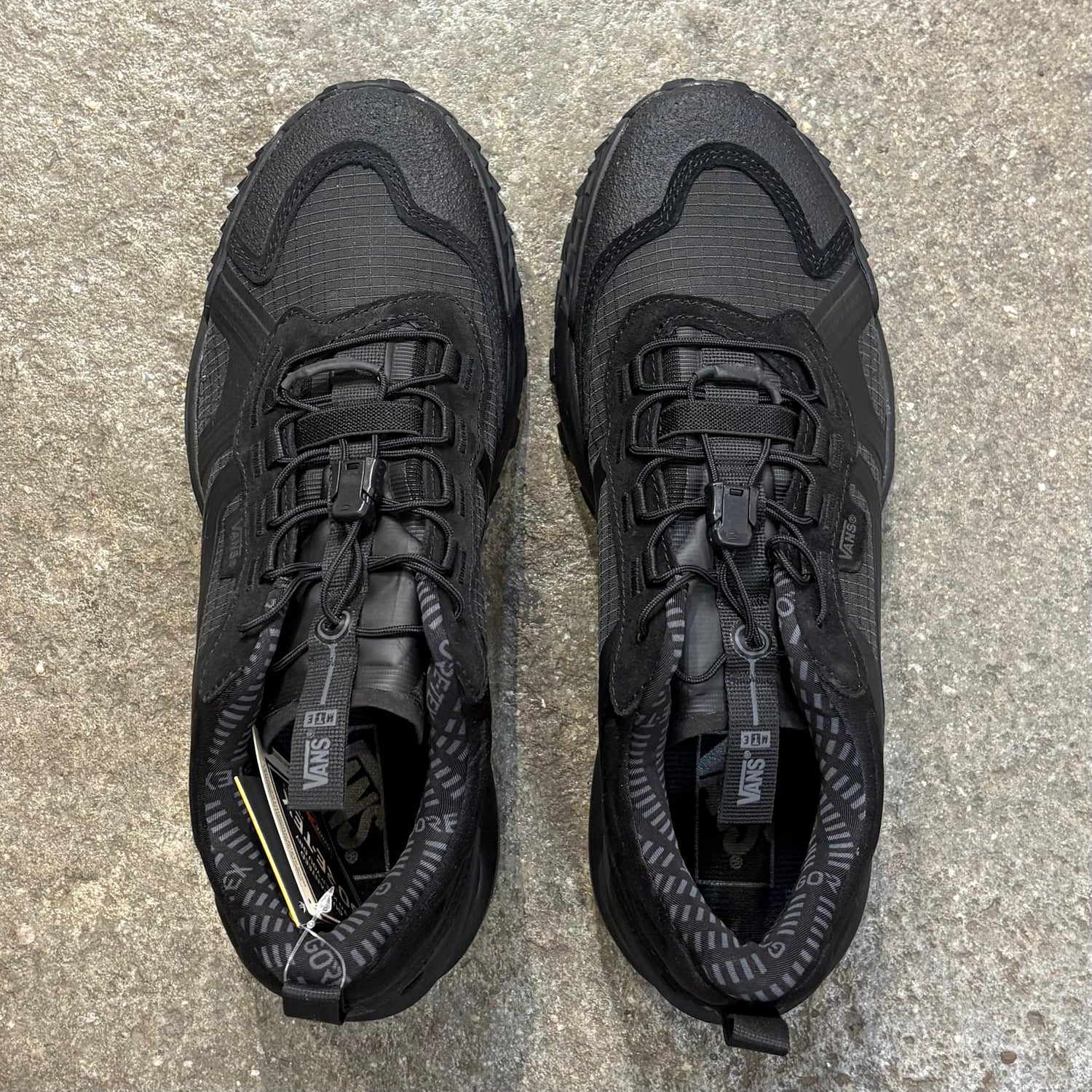 Pair of black hiking shoes on a concrete surface