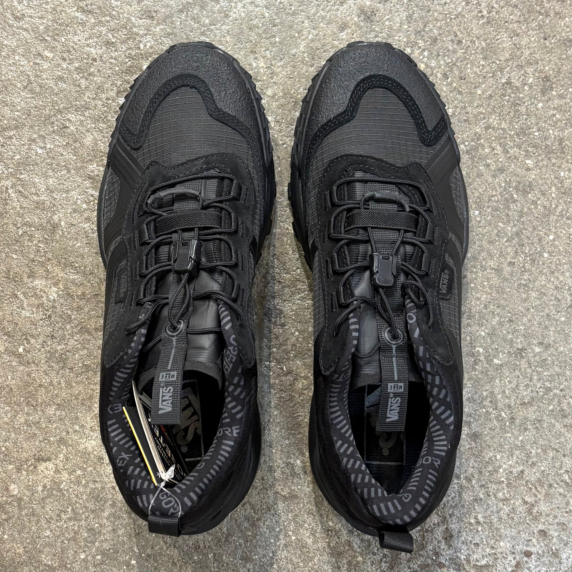 Pair of black hiking shoes on a concrete surface