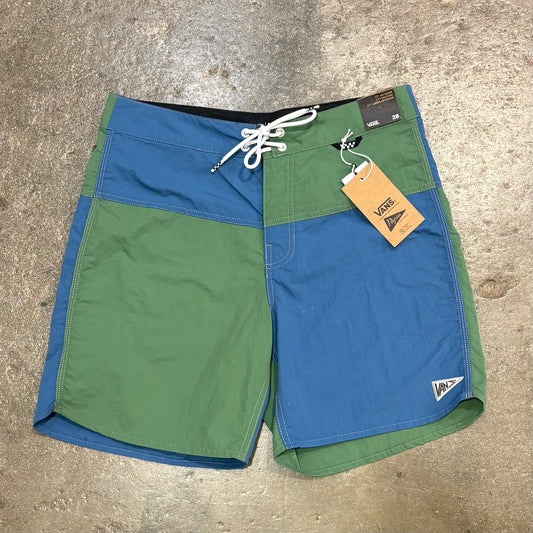 Green and blue shorts with a Vans tag on a concrete surface