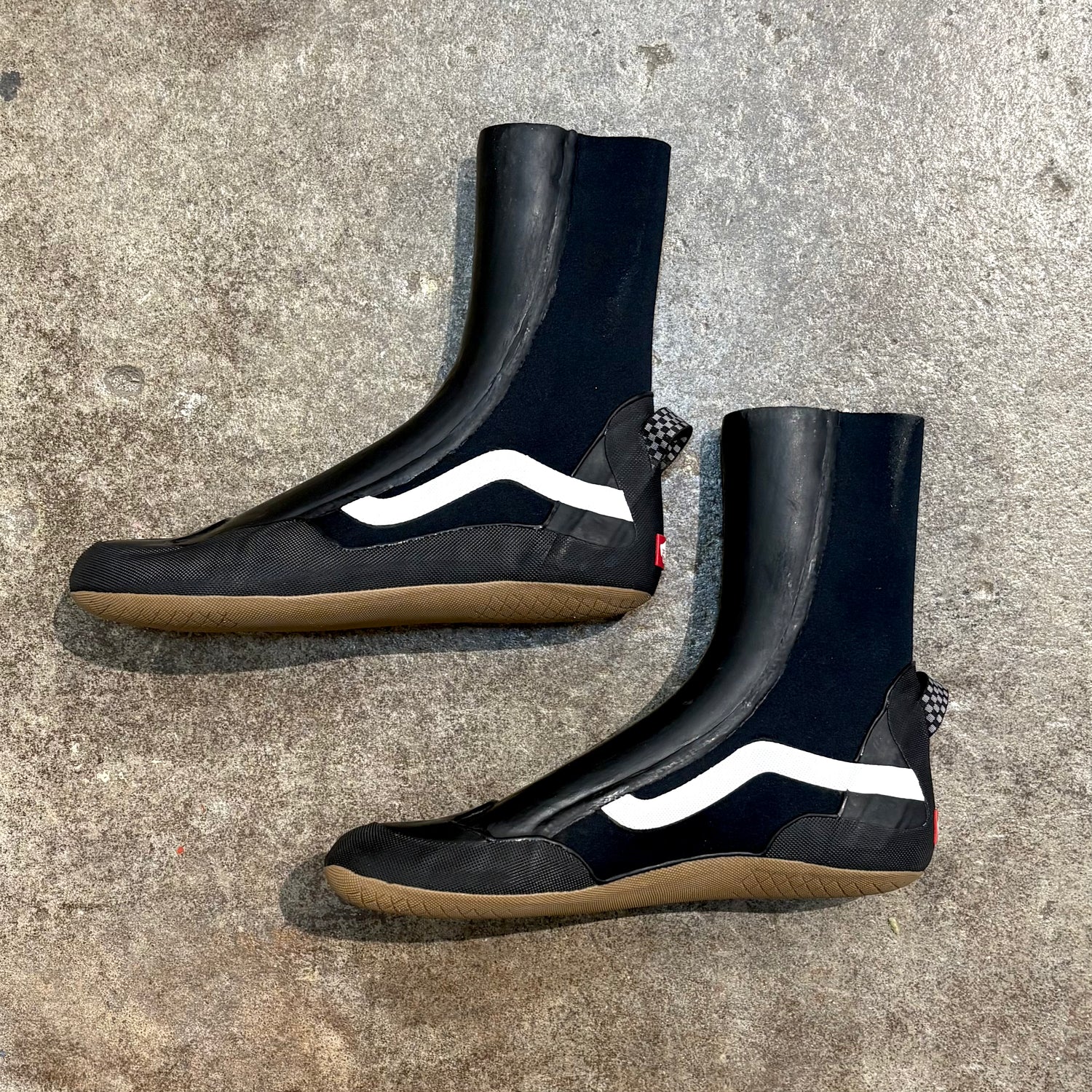 Black rubber boots with white stripes on a concrete surface