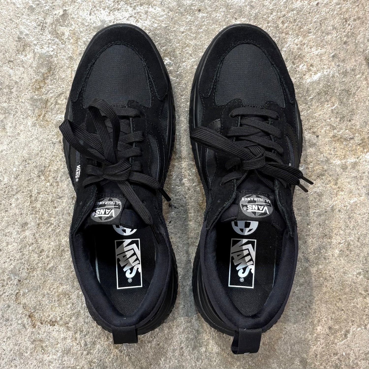 Pair of black Vans Ultrarange Neo Black/Black sneakers on a textured surface.