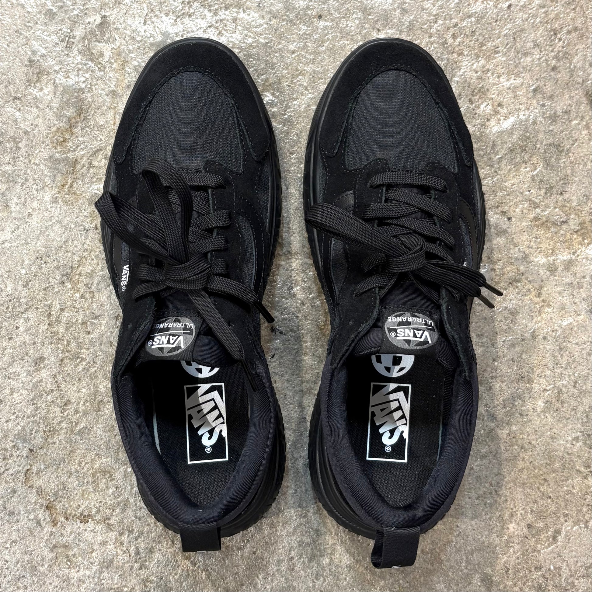 Pair of black Vans Ultrarange Neo Black/Black sneakers on a textured surface.
