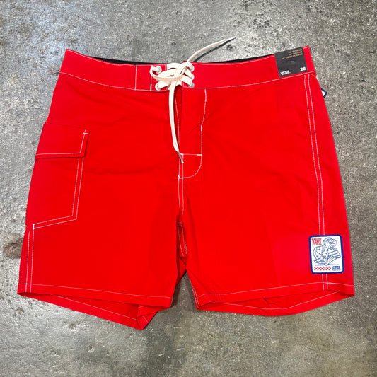 Red board shorts with a patch on a concrete surface