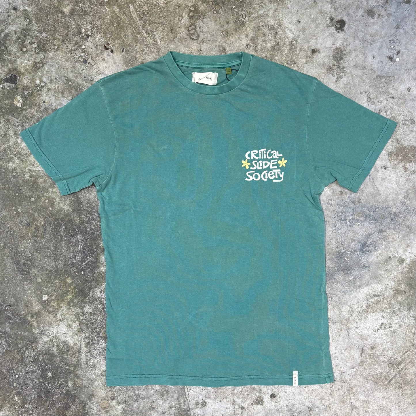 Teal t-shirt with a logo on a textured gray surface