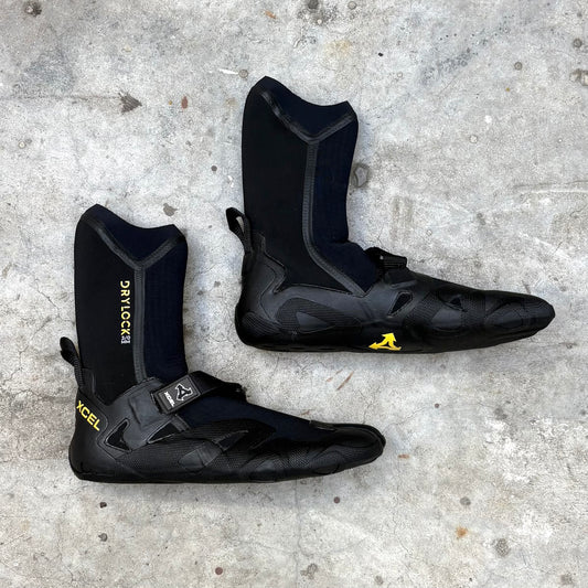 Black surfing  boots with yellow branding on a concrete surface