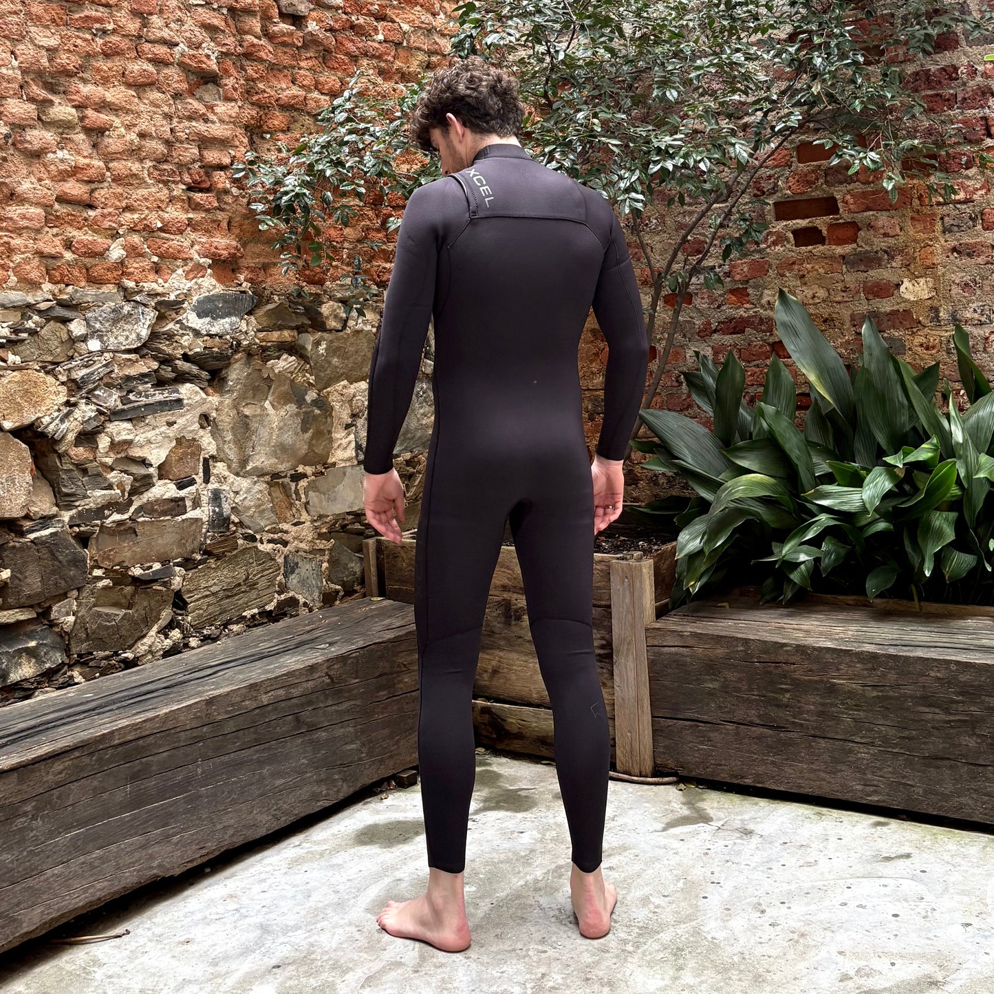 Back view of model wearing the Xcel Comp+ 4/3mm - Black - Men's Full Wetsuit