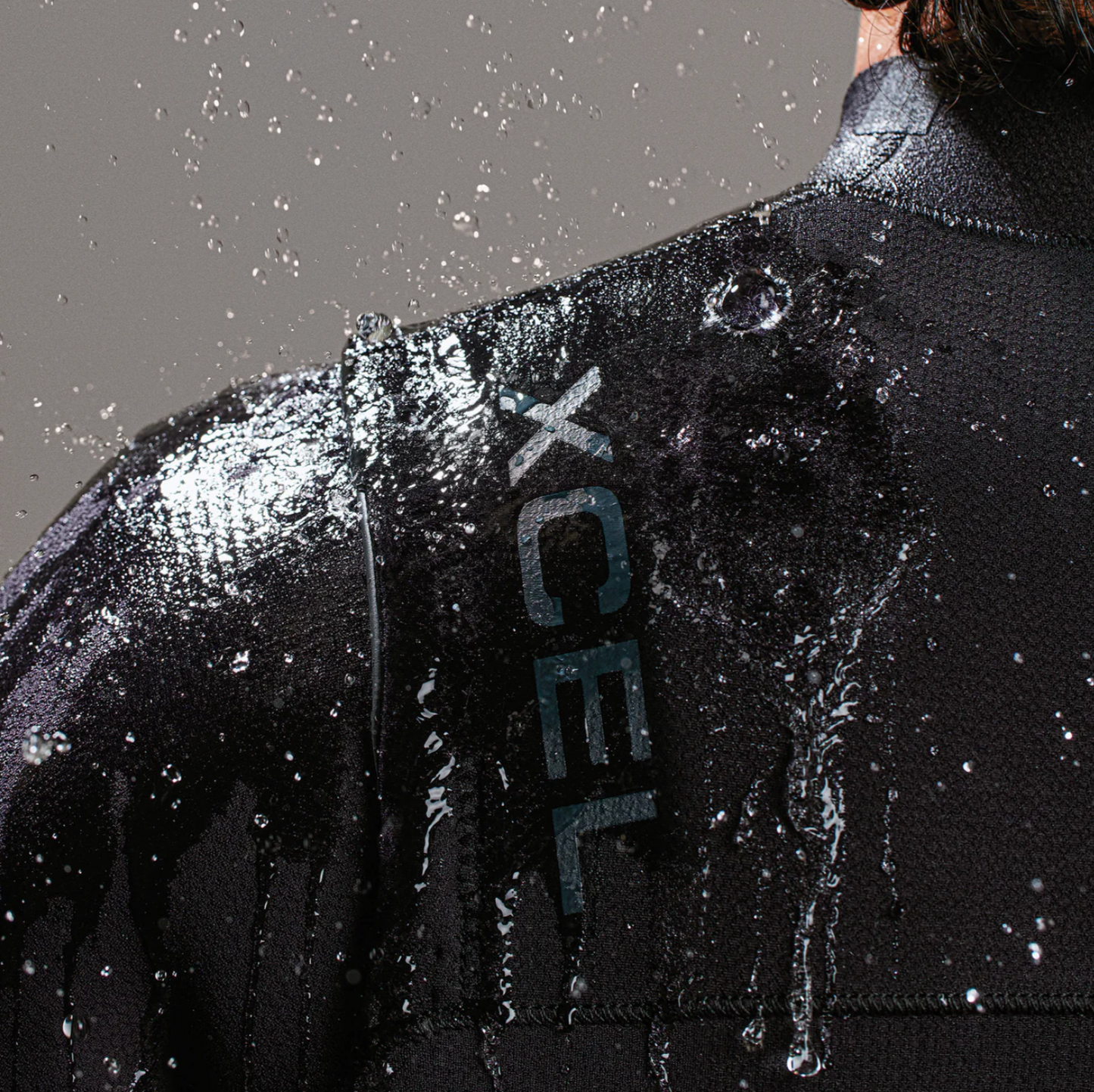 View of water splashing off model wearing the Xcel Comp+ 4/3mm - Black - Men's Full Suit
