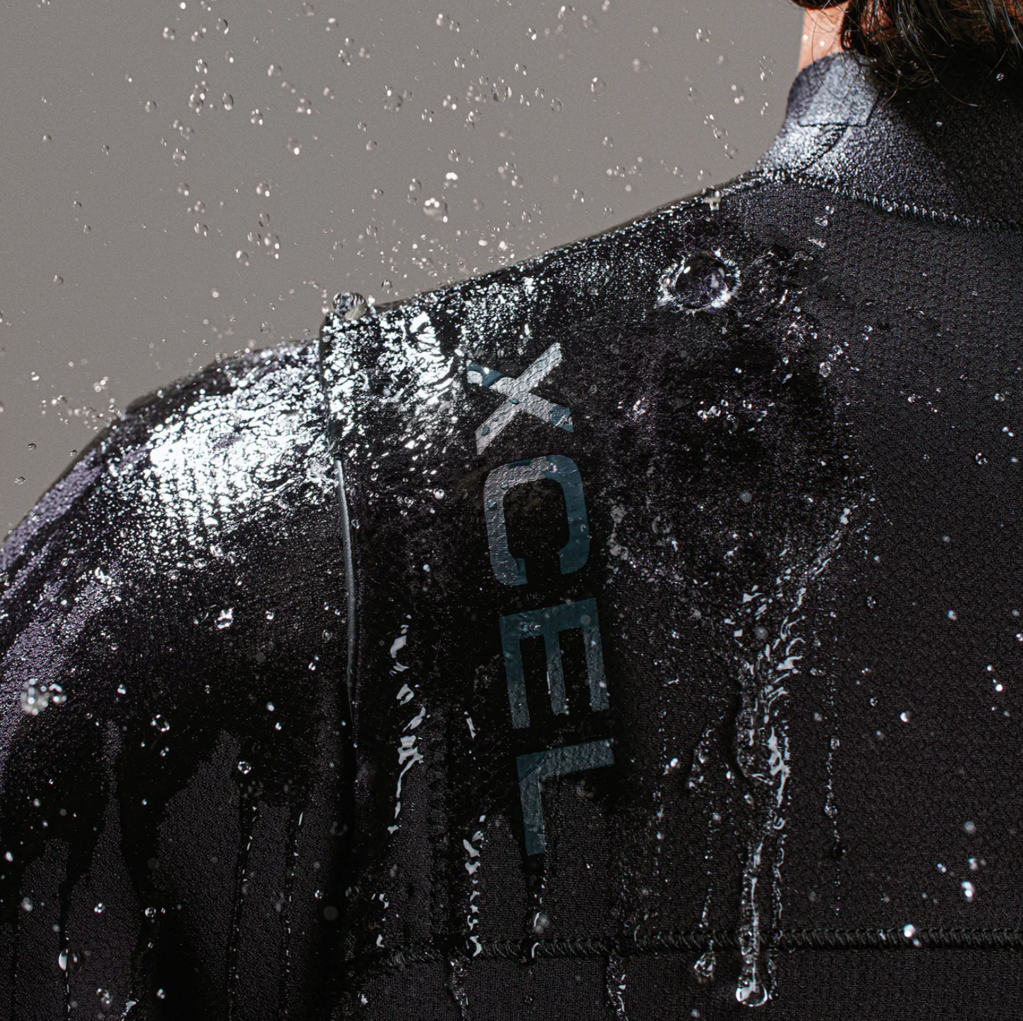 View of water splashing off model wearing the Xcel Comp+ 4/3mm - Black - Men's Full Suit