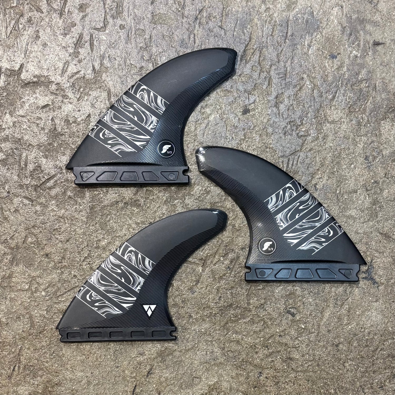 Three black and white patterned fins on a textured surface