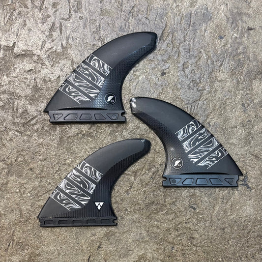 Three black and white patterned fins on a textured surface