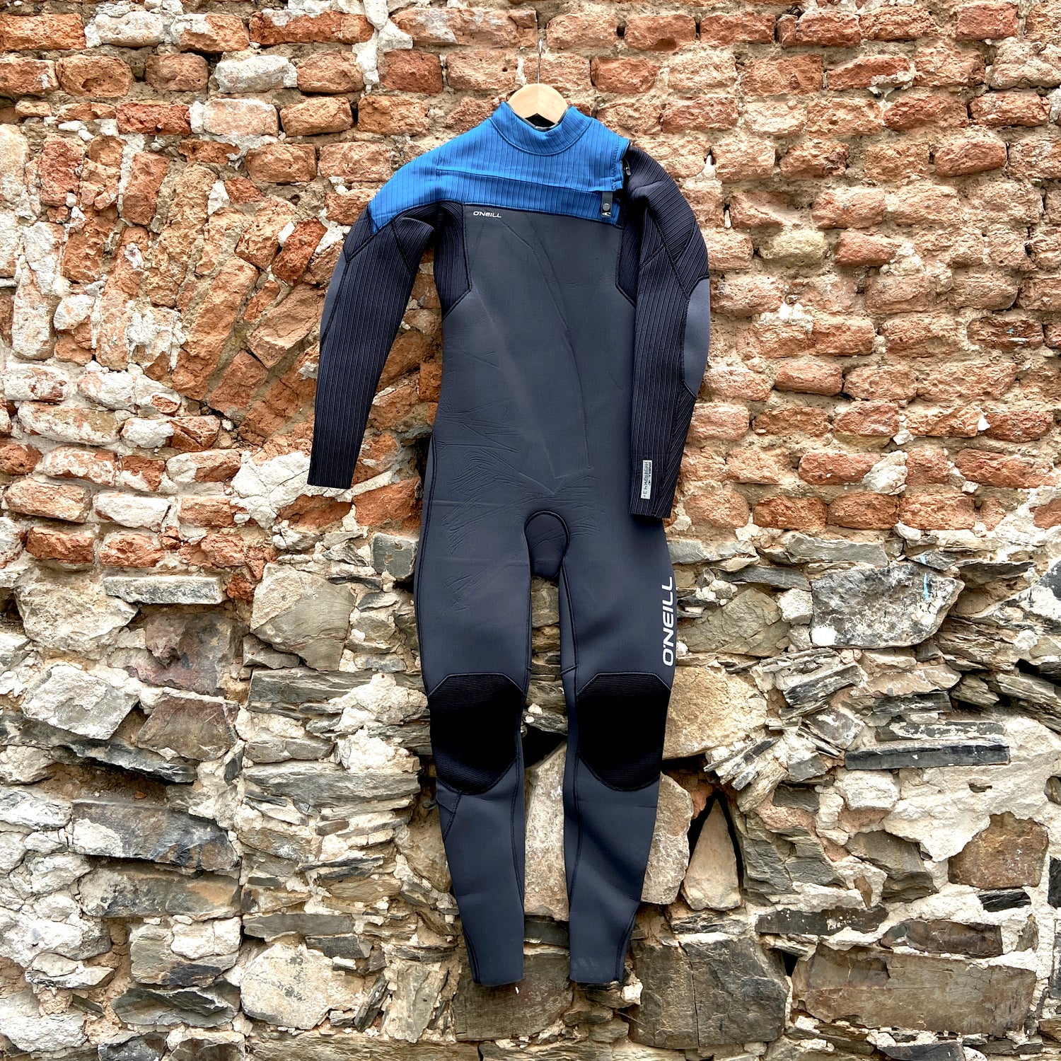 Front view of the O'Neill Youth Hyperfreak 4/3mm+ Chest Zip against brick wall - Black and Blue - Kid's wetsuit