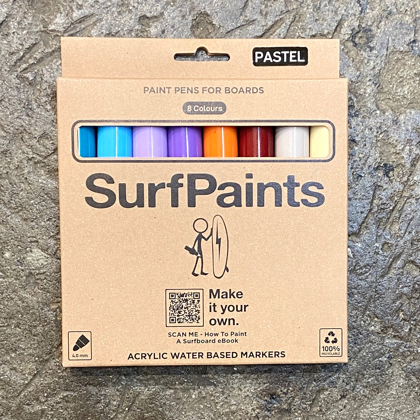A pack of SurfPaints pastel pencils for boards, featuring a range of pastel colors and a small SurfPaints logo, displayed on a textured surface.