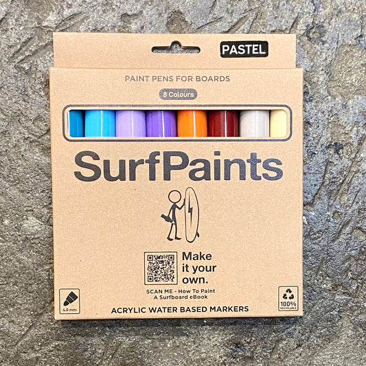 A pack of SurfPaints pastel pencils for boards, featuring a range of pastel colors and a small SurfPaints logo, displayed on a textured surface.